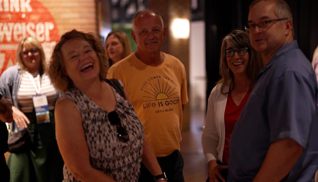people at a conference event laughing and smiling at the camera